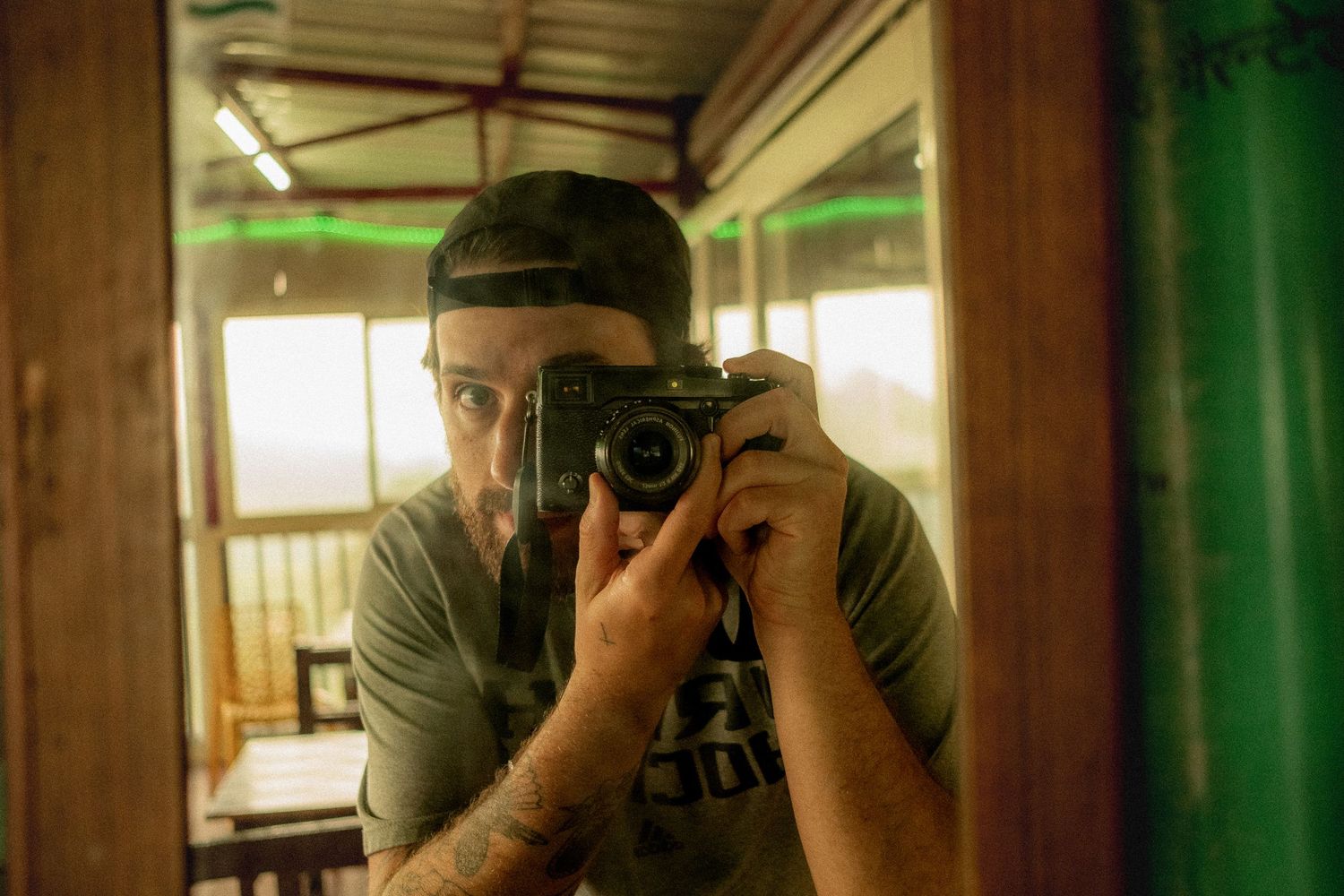 A reflection of someone taking a photograph with a vintage camera in warm, atmospheric lighting.