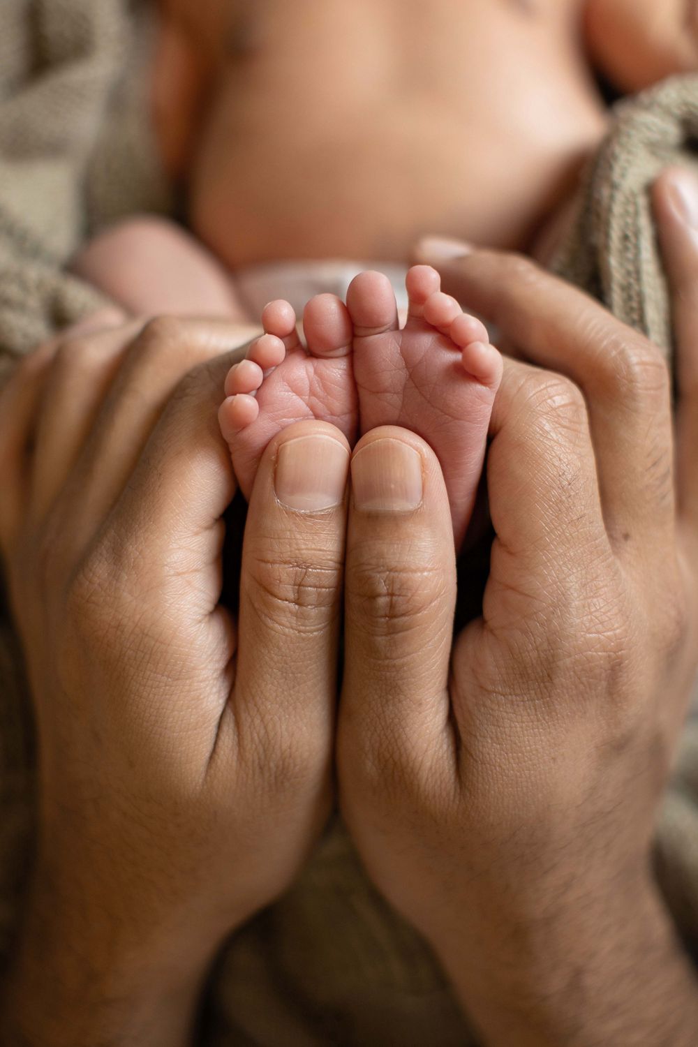 Newborn-kuvaus kotona. Yksityiskohta vauvan varpaista ja isän käsistä. Valokuvaaja Annina Nygård, pääkaupunkiseutu ja Uusimaa.