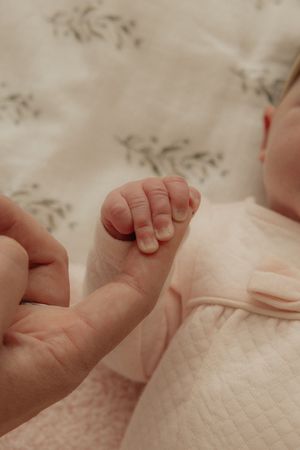 Close-up view of tiny baby feet with delicate toes against a quilted white fabric background.