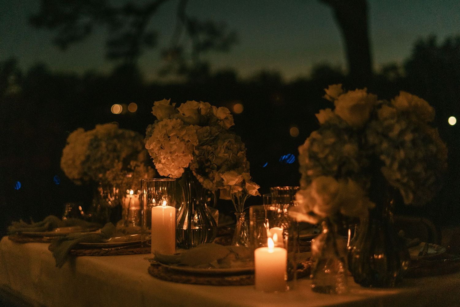 Flickering candlelight creates a warm glow through pine branches and holiday decorations at an evening event.