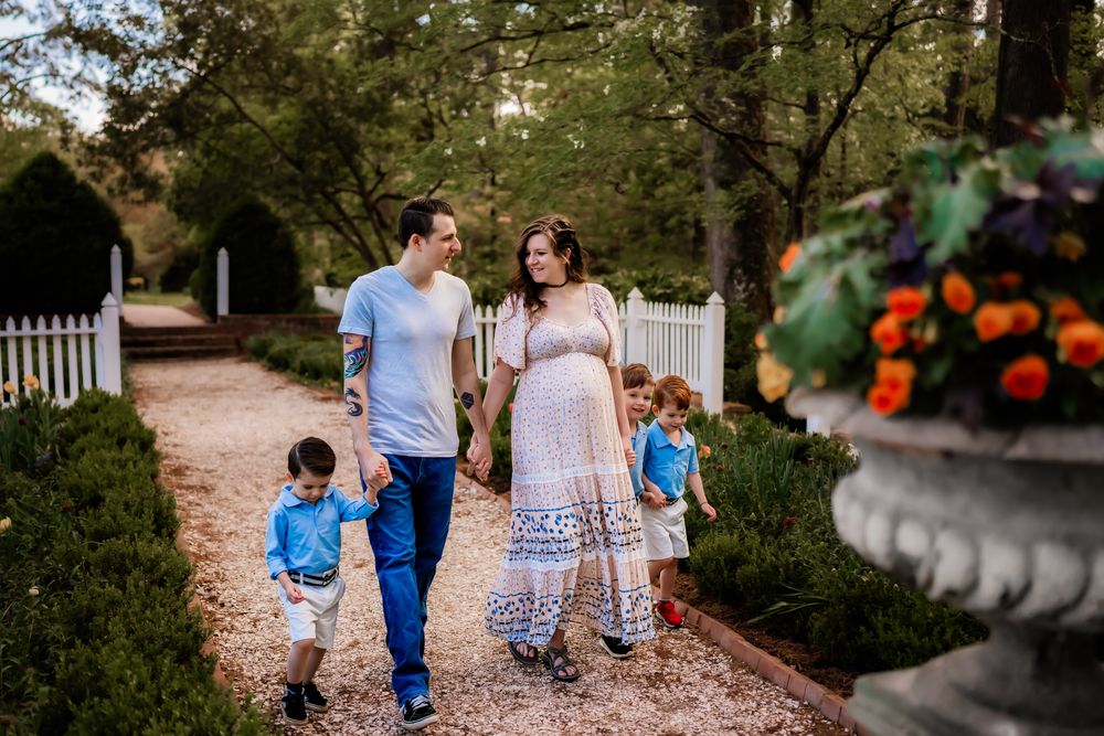 Family walking together on a tree-lined gravel path during an outdoor photo session.
