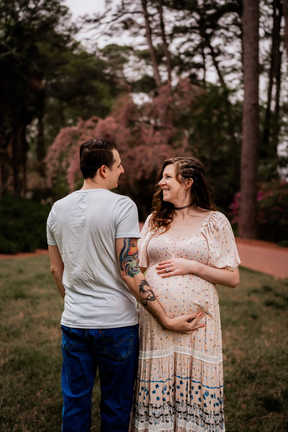A couple shares tender moments walking together in a wooded park setting during their photo session.