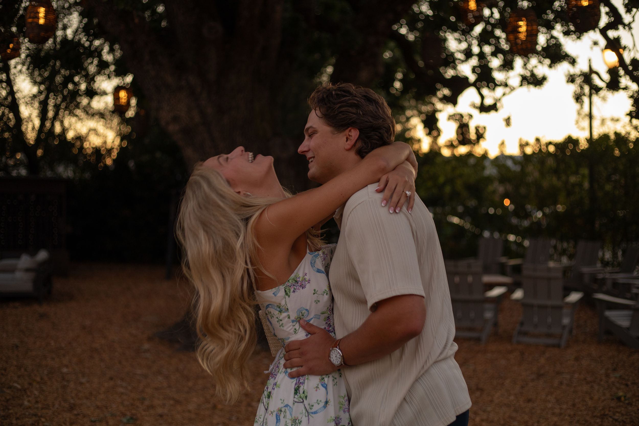 Couple wearing formal attire shares a romantic moment at sunset during an outdoor wedding photoshoot.