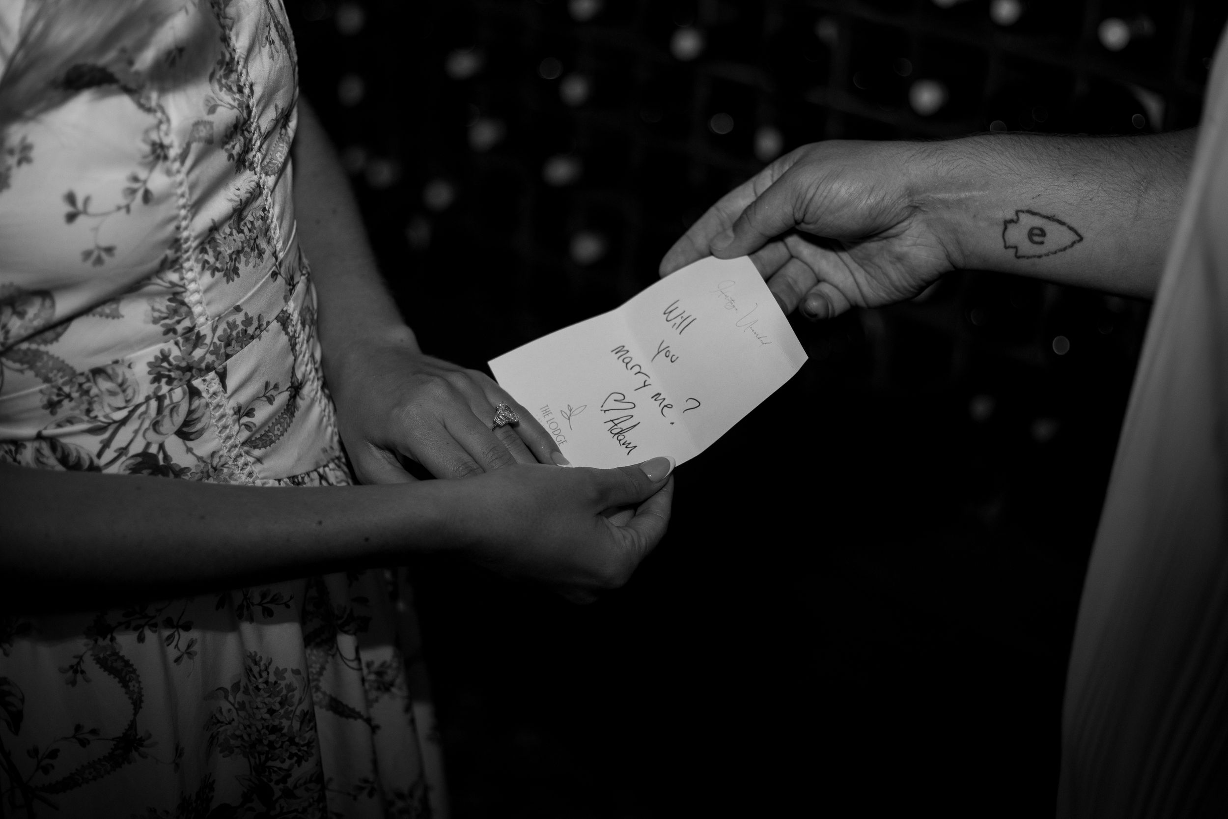 A close-up black and white shot of hands exchanging a handwritten note.