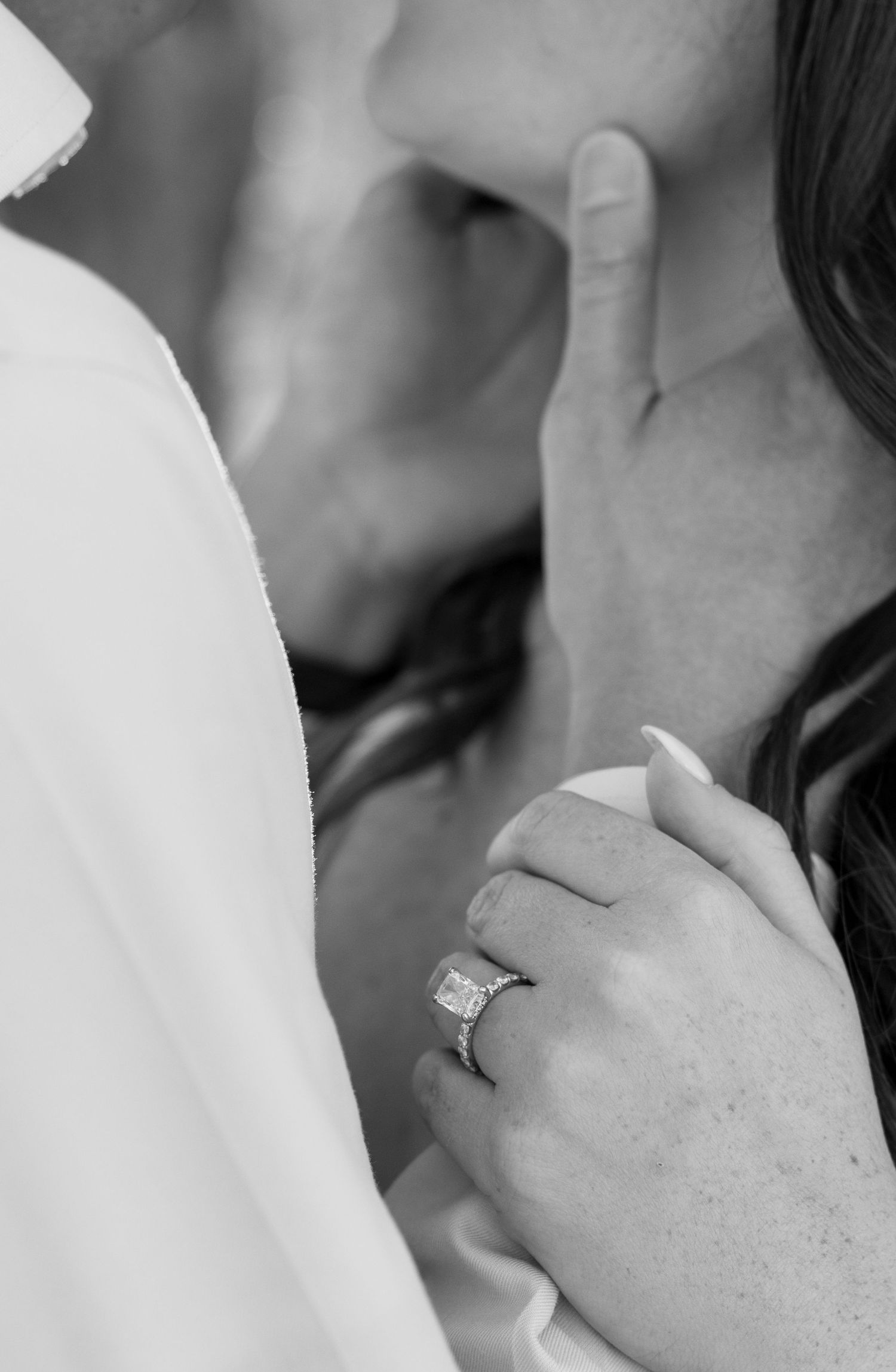 Couple embracing in a polka dot dress and white shirt against a light colored backdrop.
