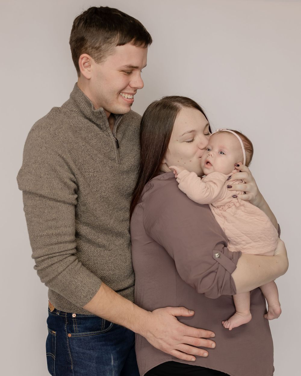 Family sharing tender moments in coordinated brown and beige outfits during intimate portrait session.