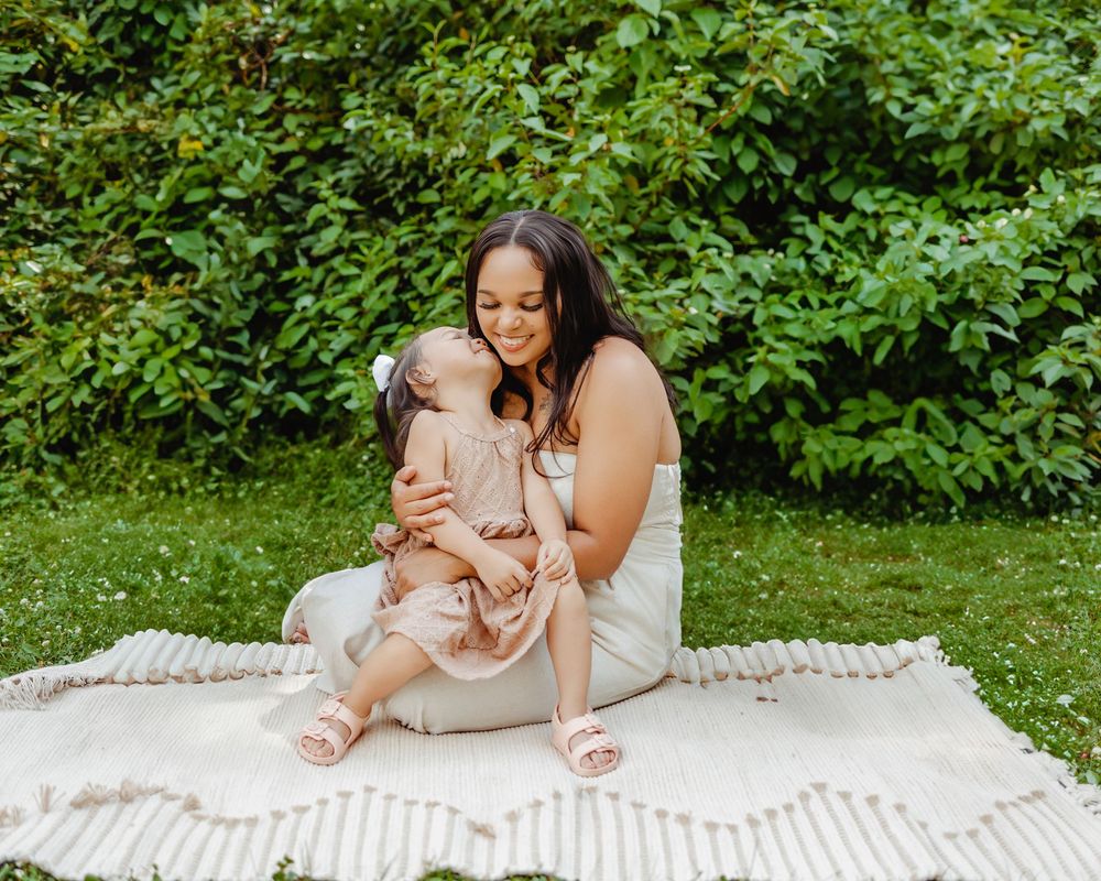 A cherished moment shared between parent and child on a white blanket surrounded by lush greenery.