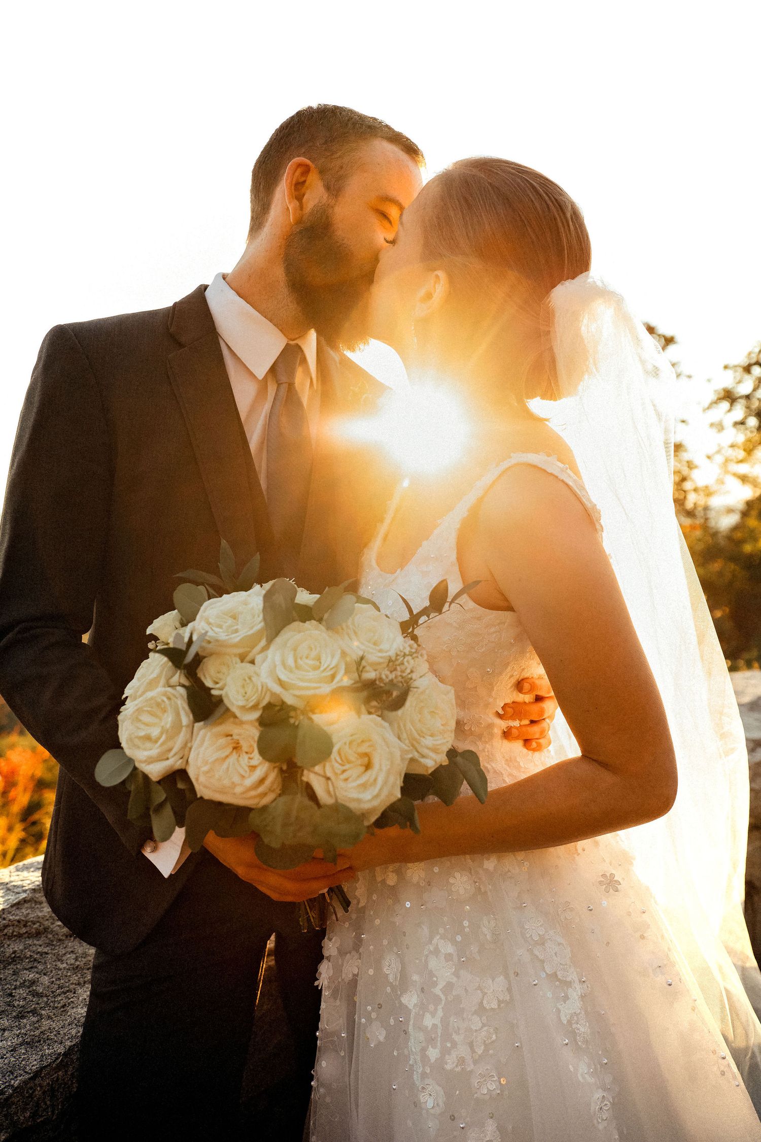 Bride and groom in sunset kissing each-other