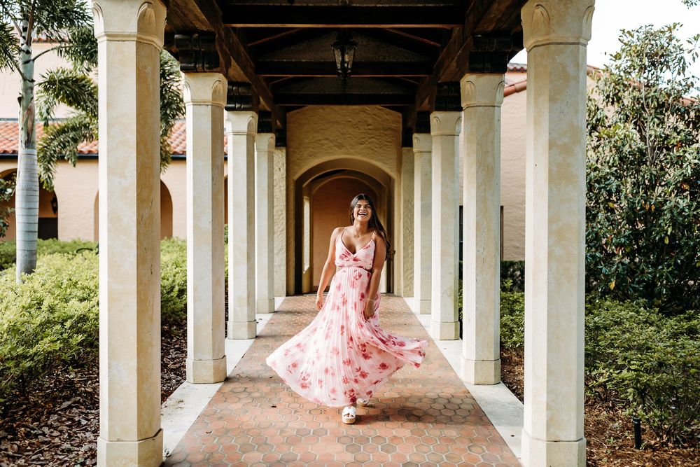 Elegant white colonnade walkway creates a beautiful architectural backdrop for a figure wearing a flowing pink dress.
