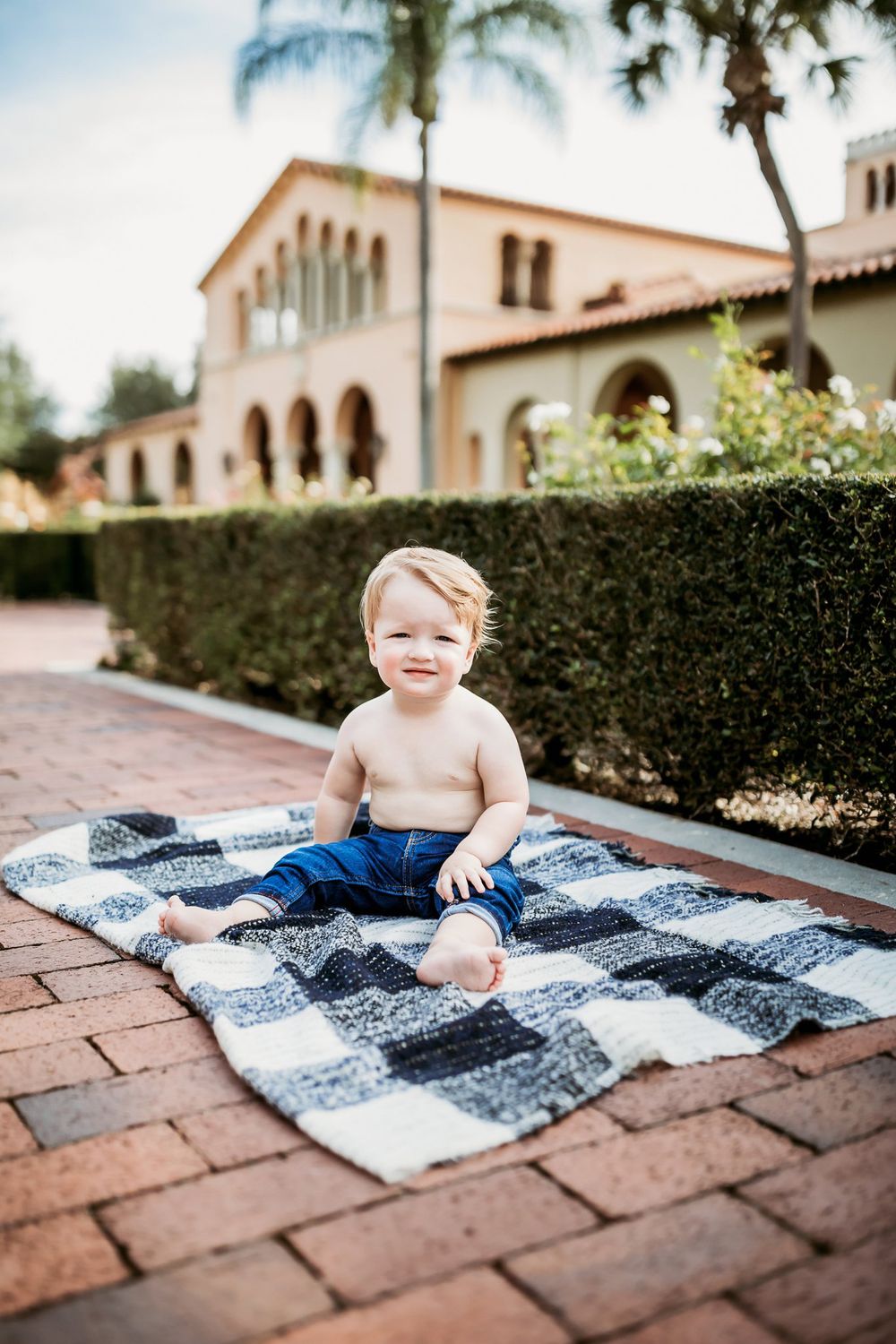 A collection of photos shows a baby on a blue and white checkered blanket on brick pavers near Mediterranean-style buildings.