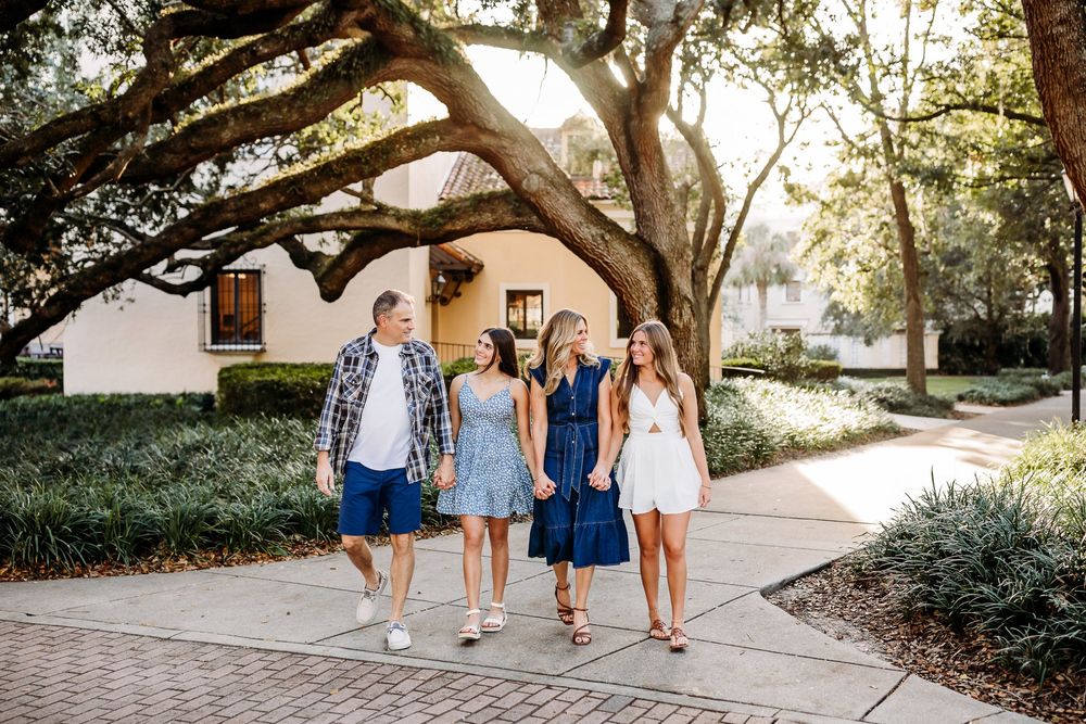 A group walks together along a sunlit pathway surrounded by lush trees and gardens in coordinated blue outfits.