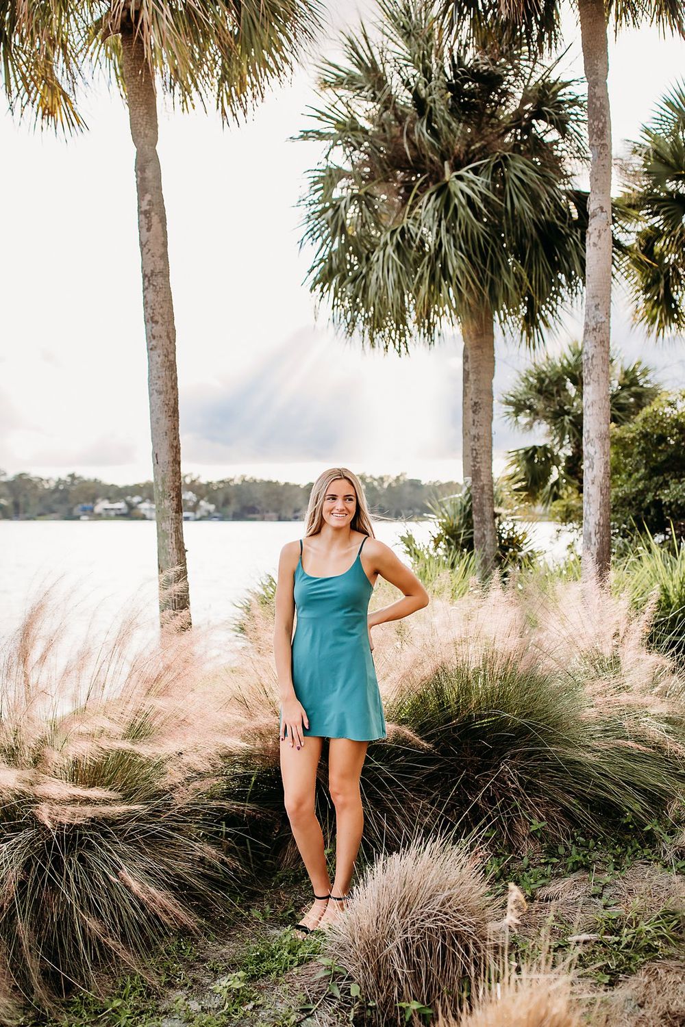 Palm trees frame a scenic coastal view with tall ornamental grasses swaying in the breeze.