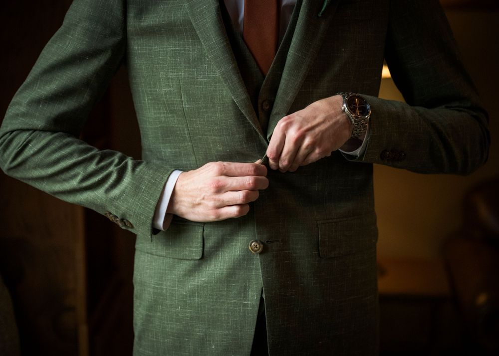 Close-up details of a green plaid suit jacket and red tie against a dark background.