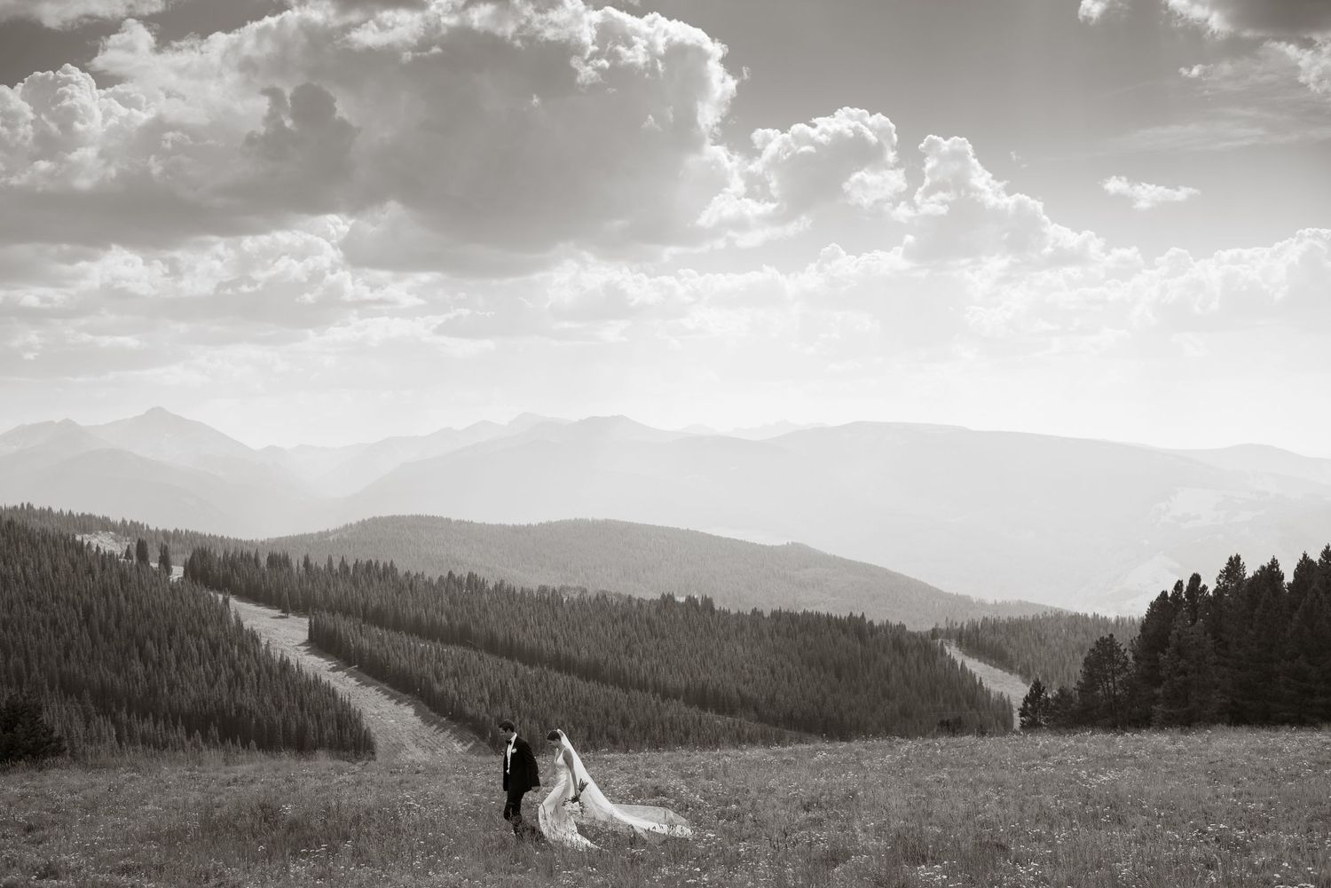 A dramatic mountain landscape with rolling hills and cloudy skies stretches into the distance.