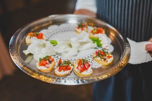 Elegant appetizers with red caviar and garnishes served on a decorative silver platter at an upscale event.