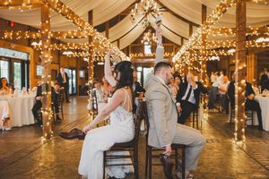 First dance at a rustic barn wedding reception decorated with warm string lights and draped fabric ceiling.