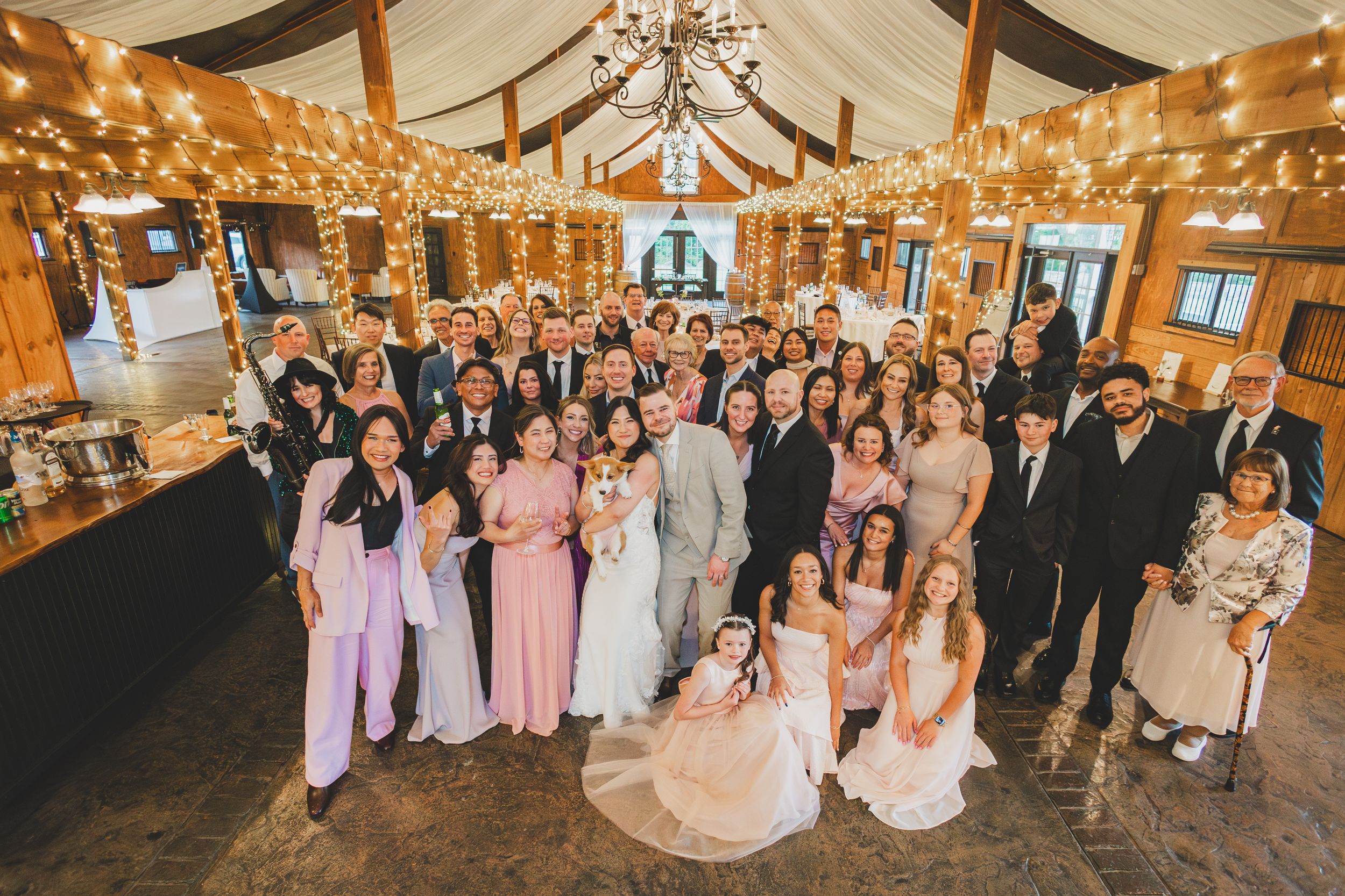 Wedding reception venue decorated with string lights and rustic wooden beams features guests enjoying the celebration.