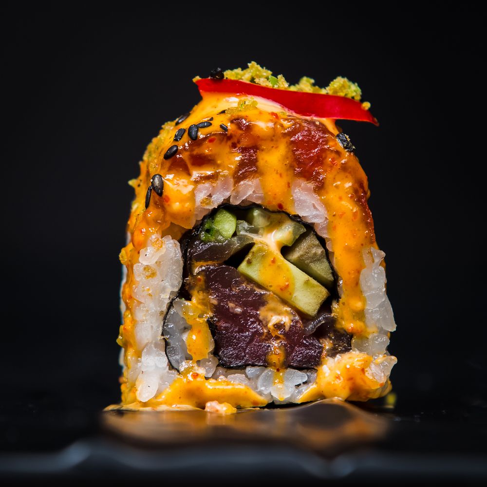 Close-up of vibrant sushi rolls with orange roe and various fillings on dark background.
