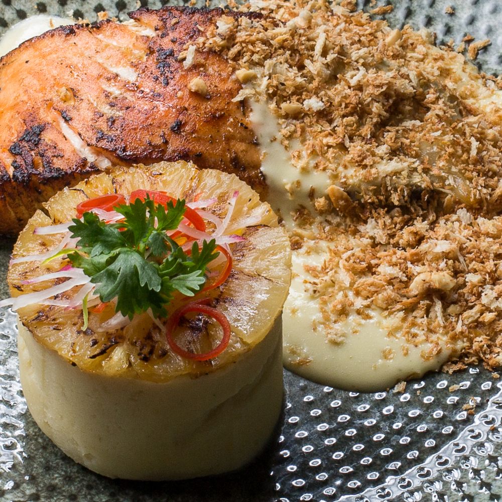 Close-up of elegant appetizers with crunchy toppings and fresh herbs on patterned plates.