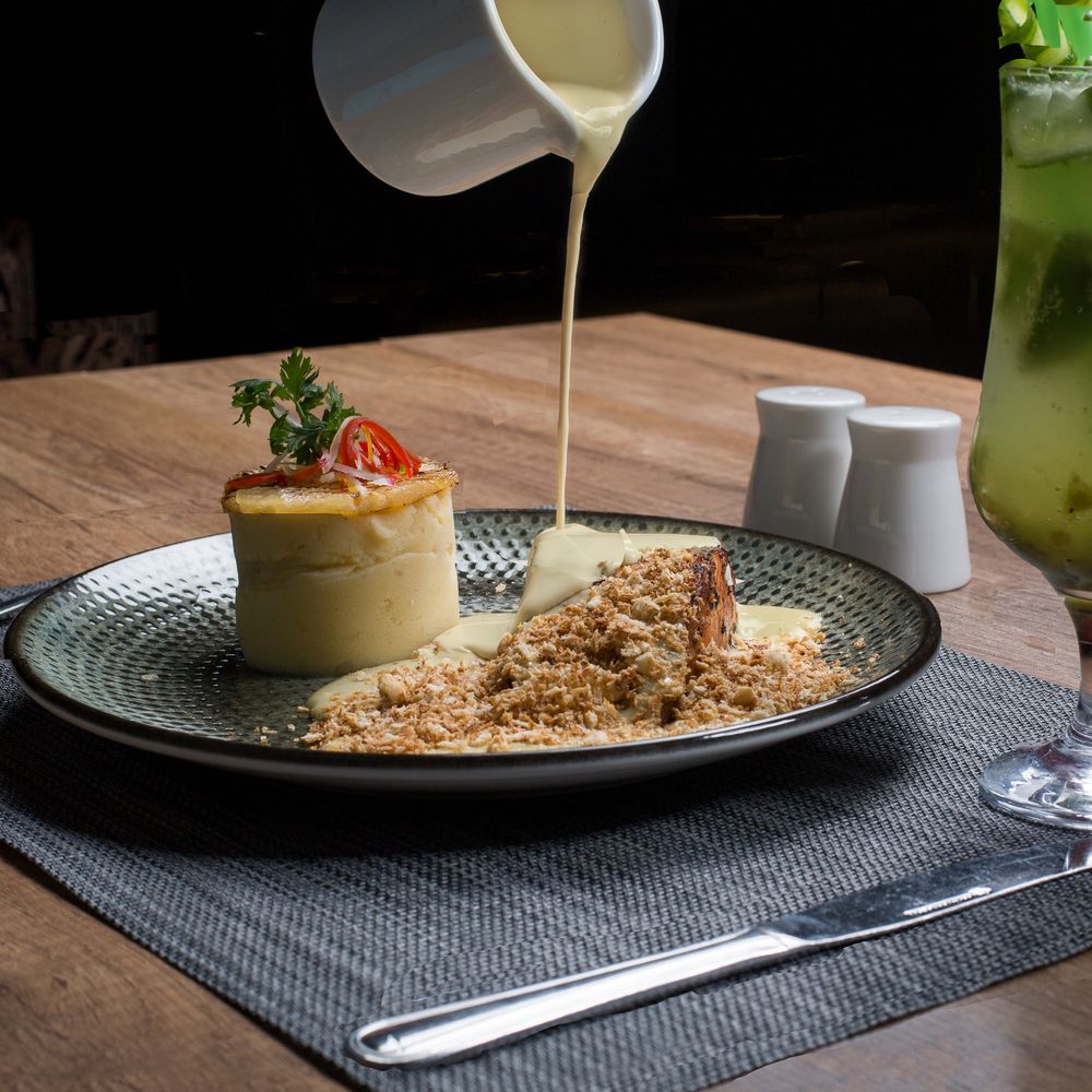 Elegant plating of creamy appetizer with crumb topping on textured plates with modern place settings.