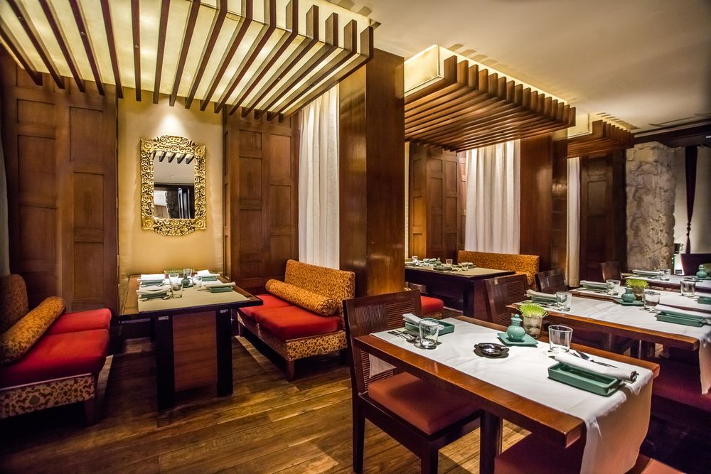 Modern restaurant interior with wood paneled walls and red accent furniture.