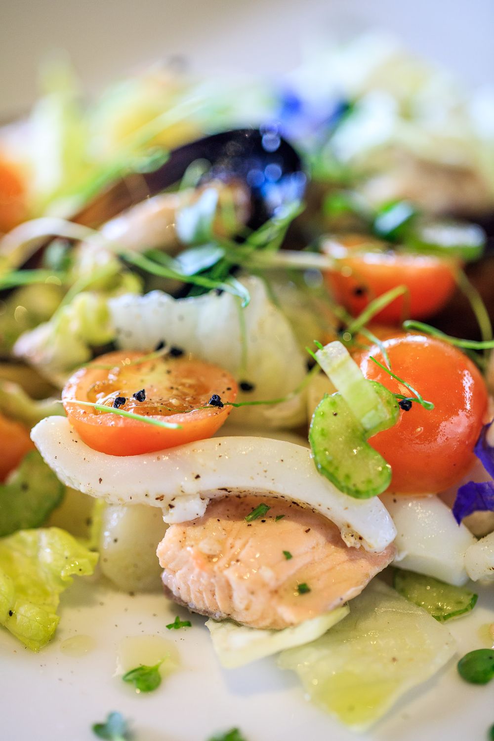 Fresh seafood salad with cherry tomatoes and edible flowers in a light dressing.