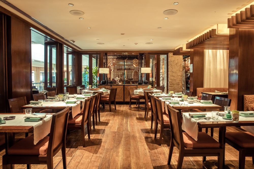 Modern upscale restaurant dining room with wooden tables and warm lighting.