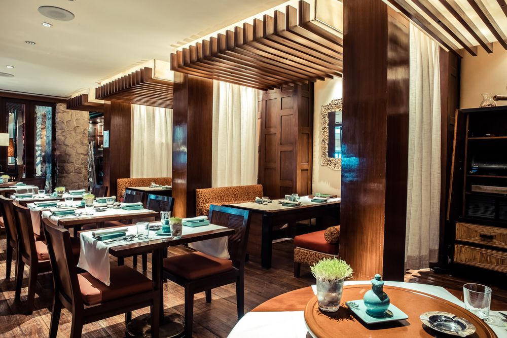 Contemporary restaurant interior with wooden columns and modern lighting fixtures.