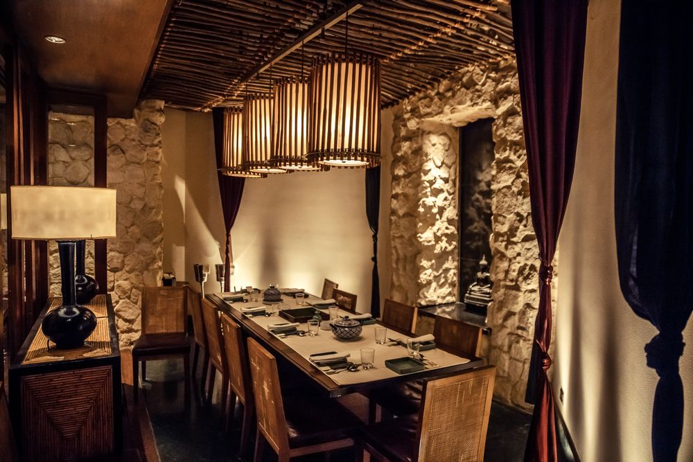 Intimate dining space with stone walls and wooden ceiling details lit by warm lighting.