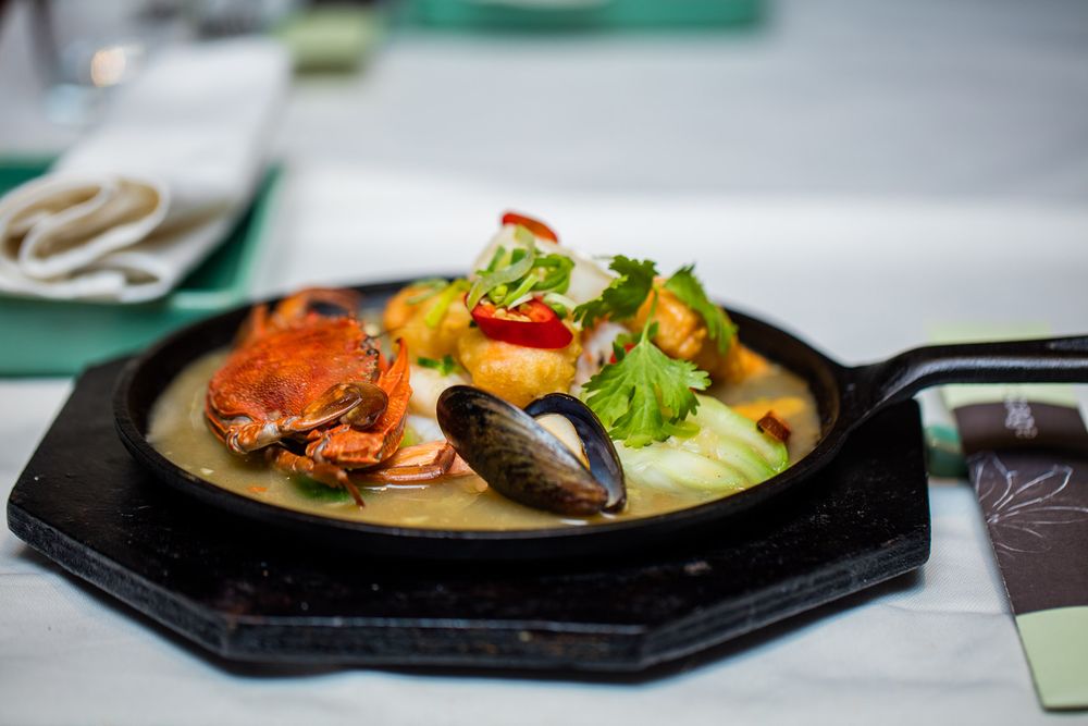 Beautifully plated gourmet dishes served on dark plates with colorful garnishes.
