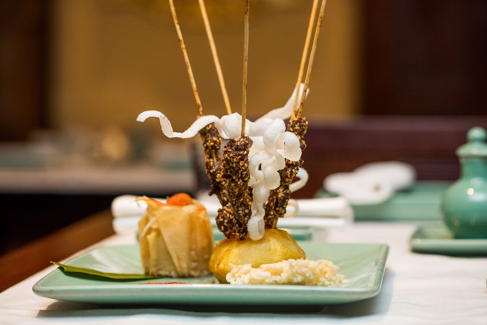 Delicate appetizers presented on modern turquoise plates with decorative garnishes.