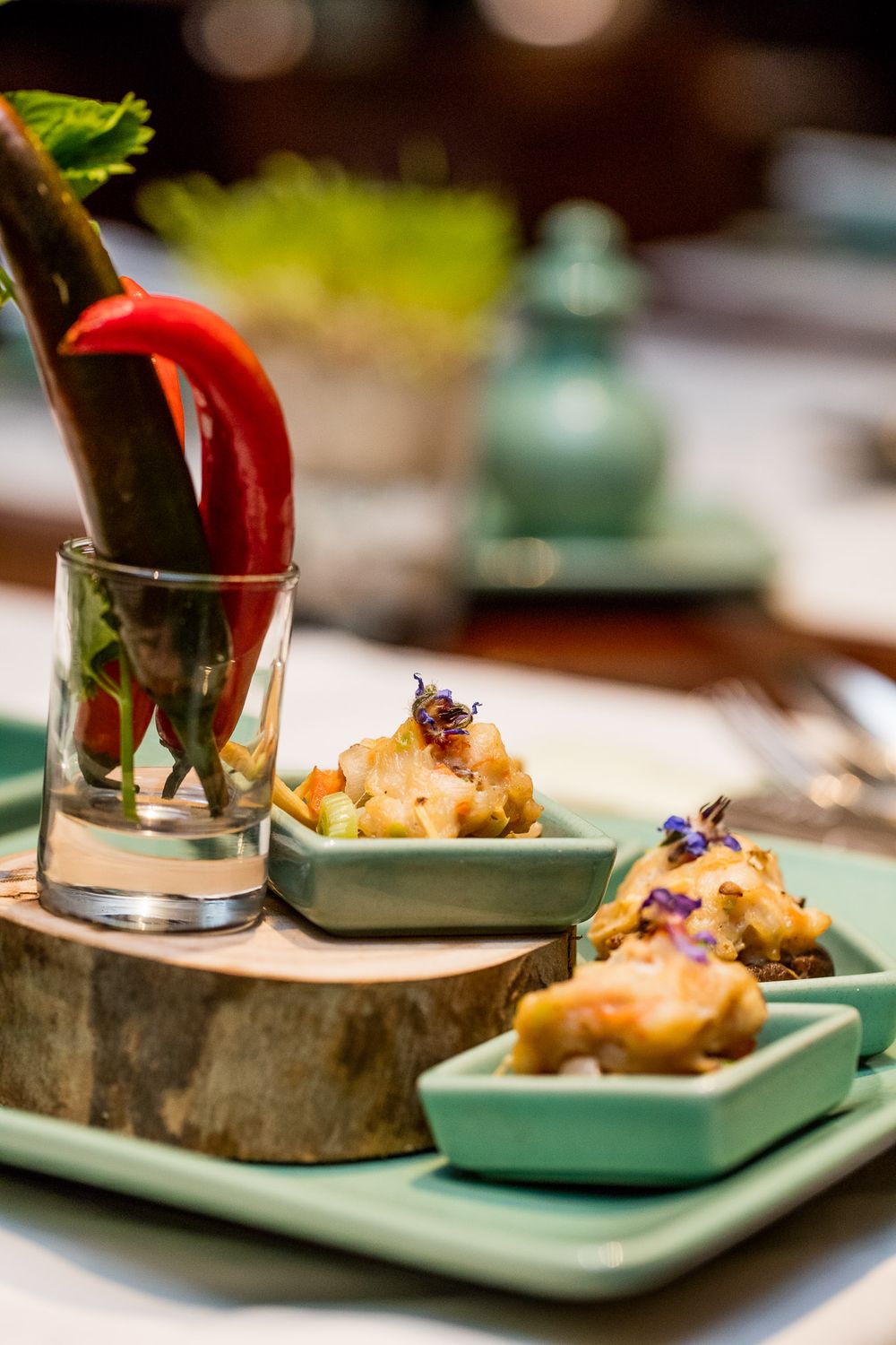 Artistic appetizers served on turquoise plates with red pepper garnish.