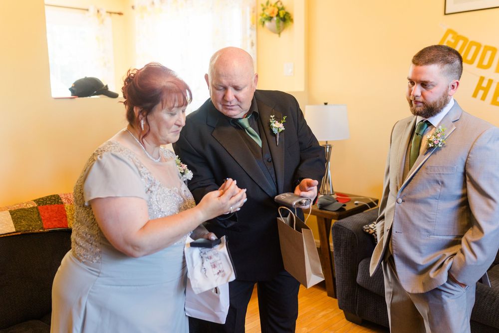 Three people check their phones while standing in a yellow-walled room at an event.