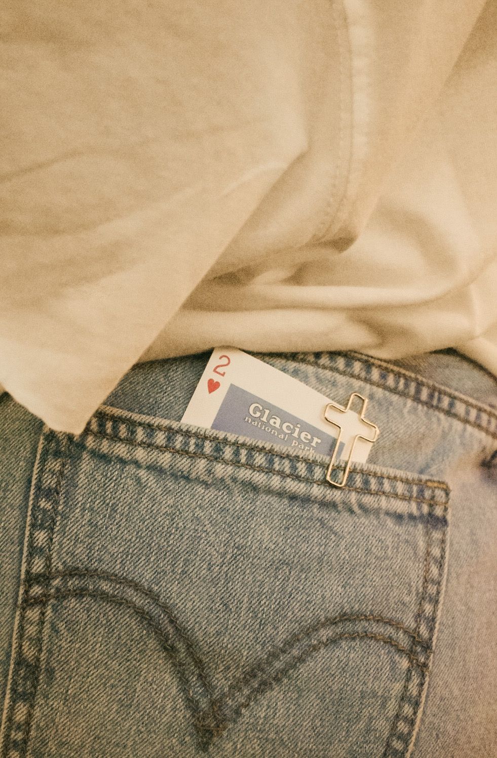 Playing card sticking out of a back pocket of classic blue denim jeans with visible pocket stitching detail.