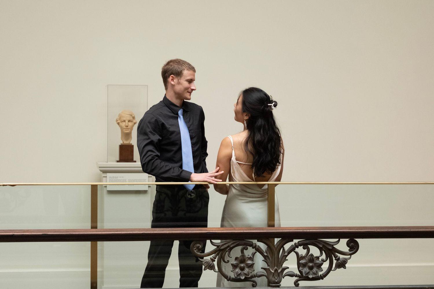 A couple walks through an elegant museum gallery space with artwork on display.