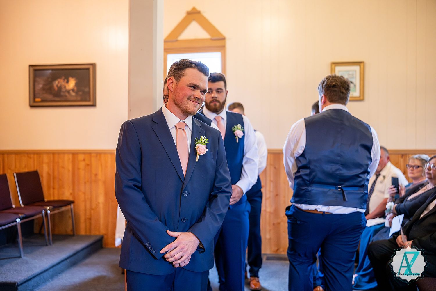 Groomsmen in navy suits and pink ties share laughs during pre-wedding gathering.