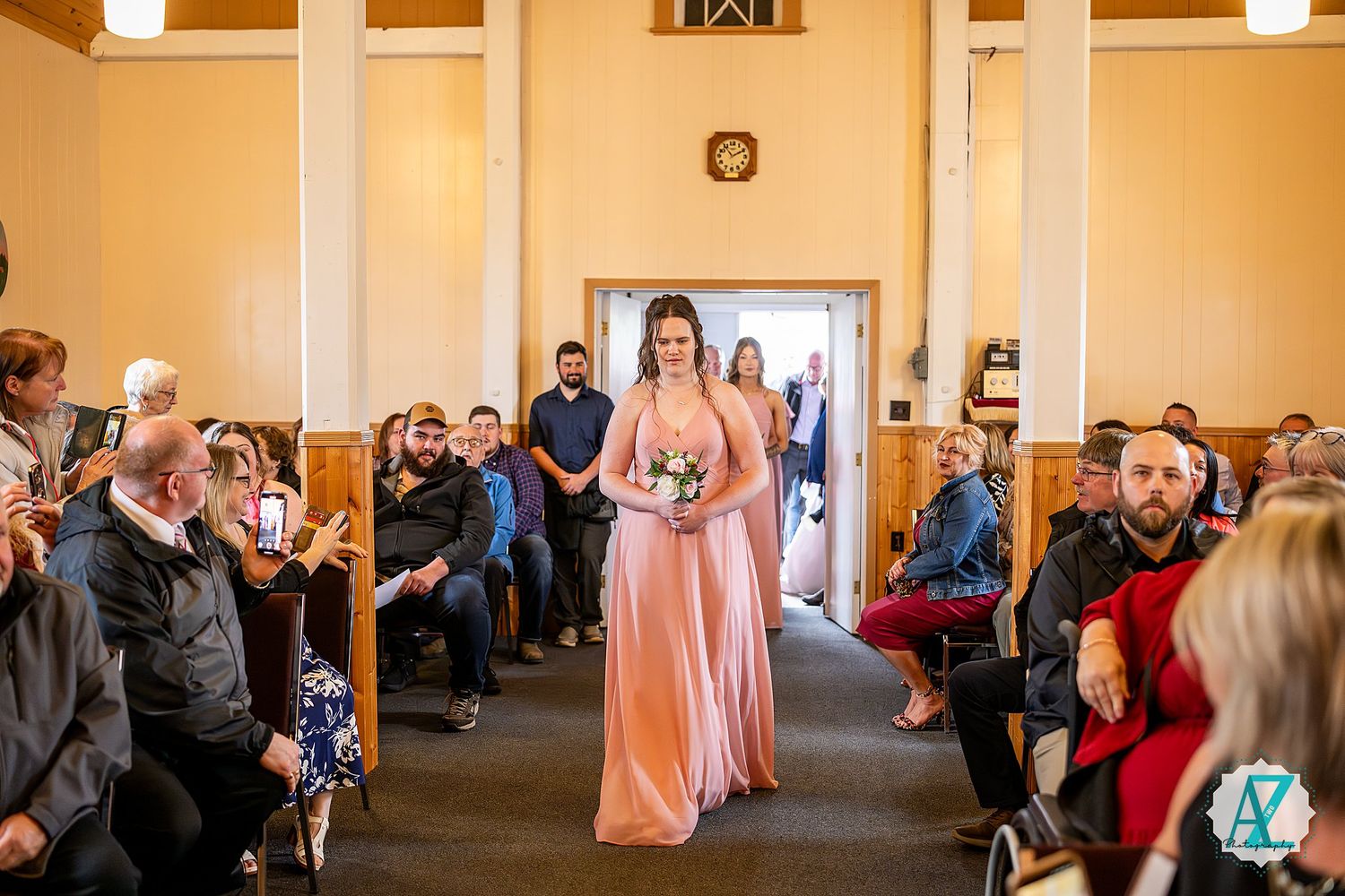 Wedding guests gathering in a church hall with wooden beams and warm lighting.