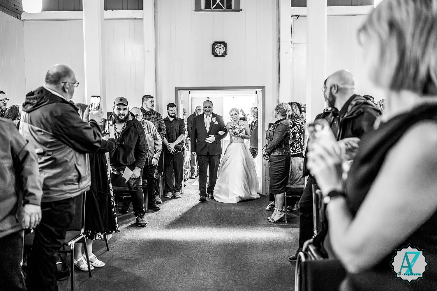 A lively crowd dances and celebrates on the dance floor at a monochromatic black and white wedding reception.
