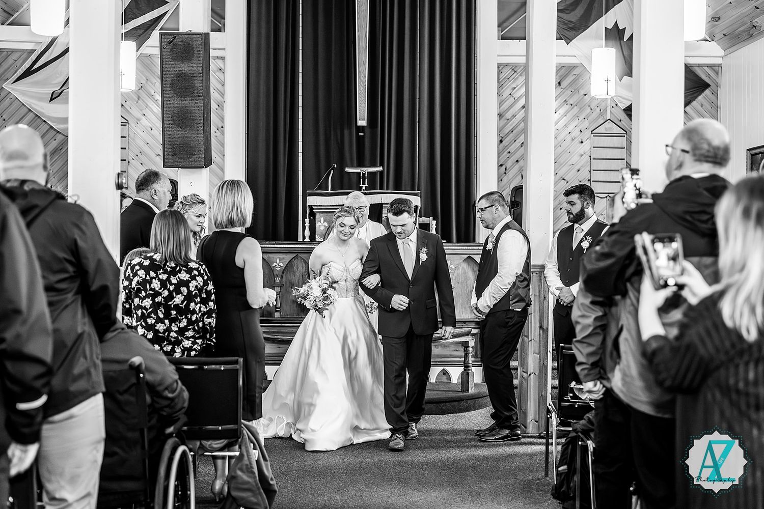 Black and white photo of wedding celebration in church reception hall.