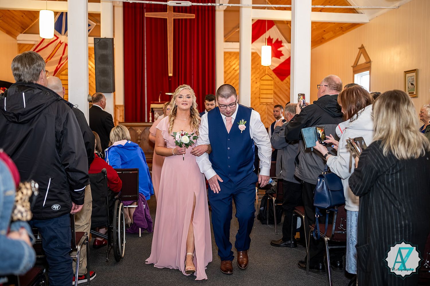Wedding guests walk through a reception venue with rustic decor and red curtains during a celebration.