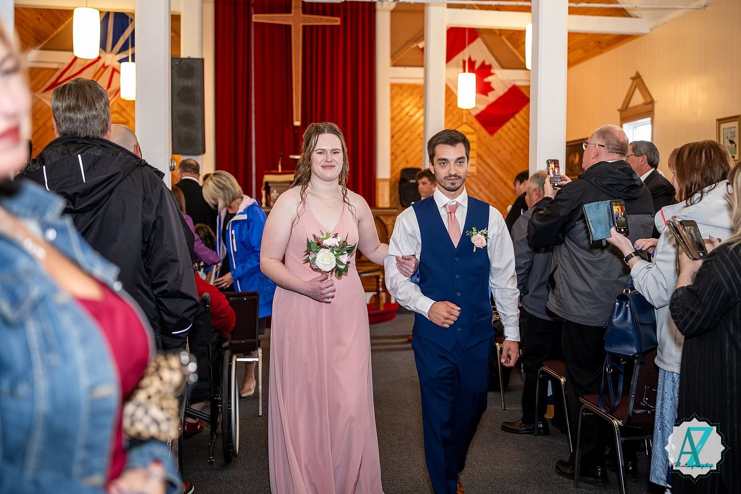 Wedding celebration with people dancing and mingling in a church reception hall with pink and navy attire.