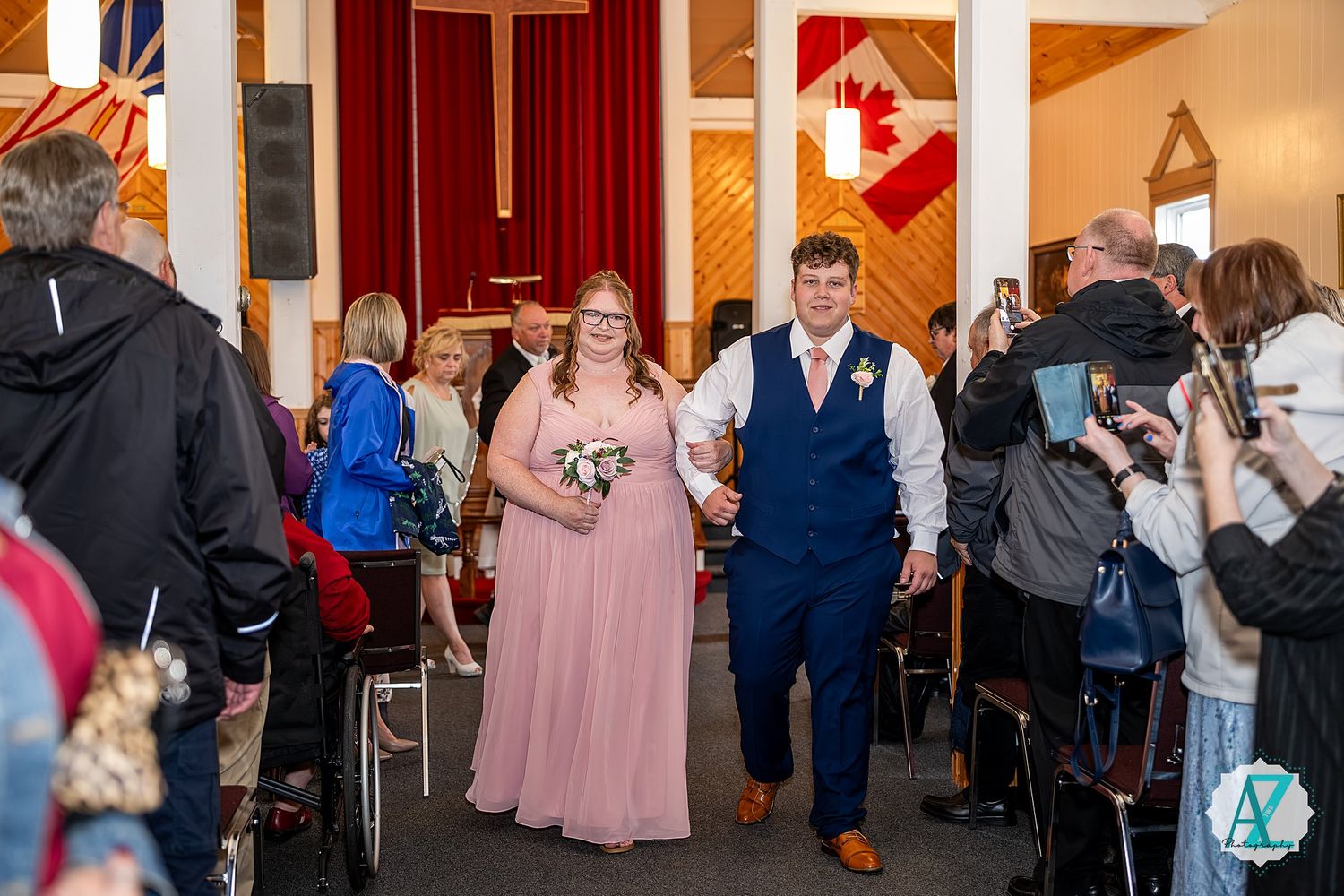 Group of wedding guests enjoying themselves dancing on a wood floor dance hall at an evening reception celebration.