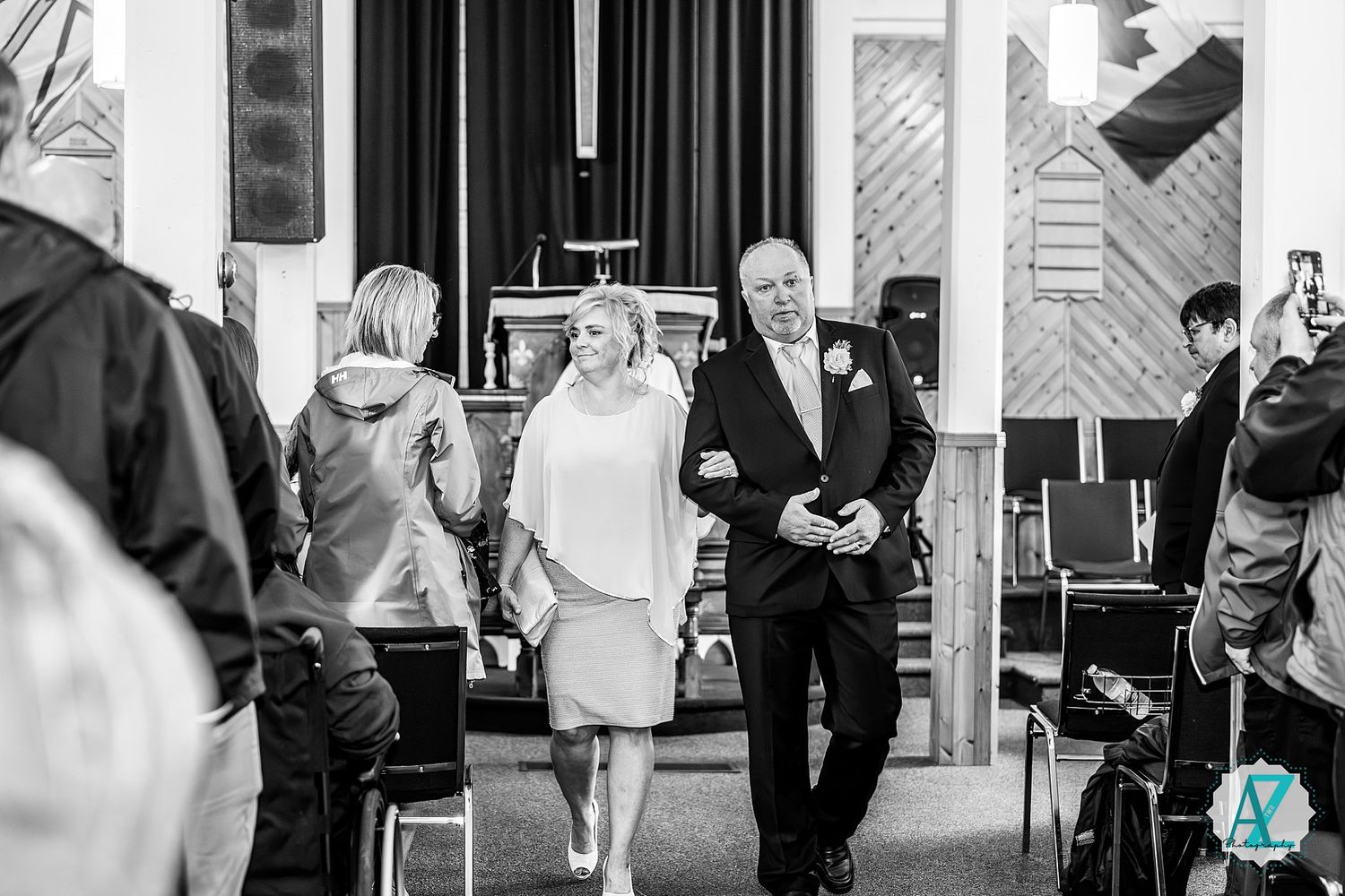 Black and white photo of wedding guests mingling and socializing at an indoor venue reception.
