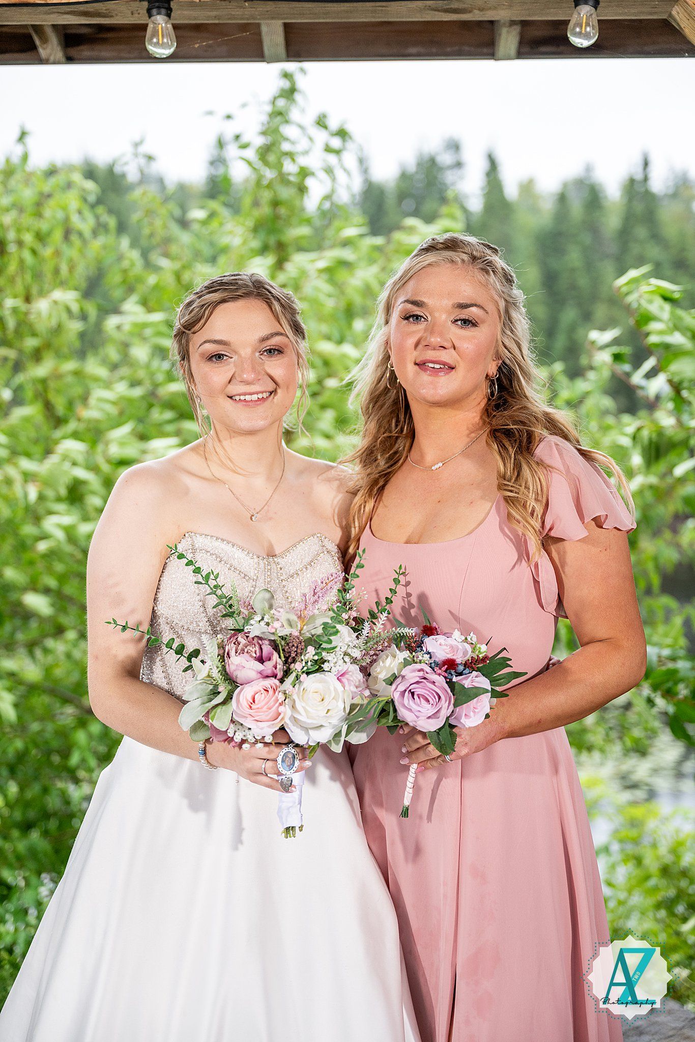 Bridesmaids in pink dresses hold matching floral bouquets while smiling outdoors.