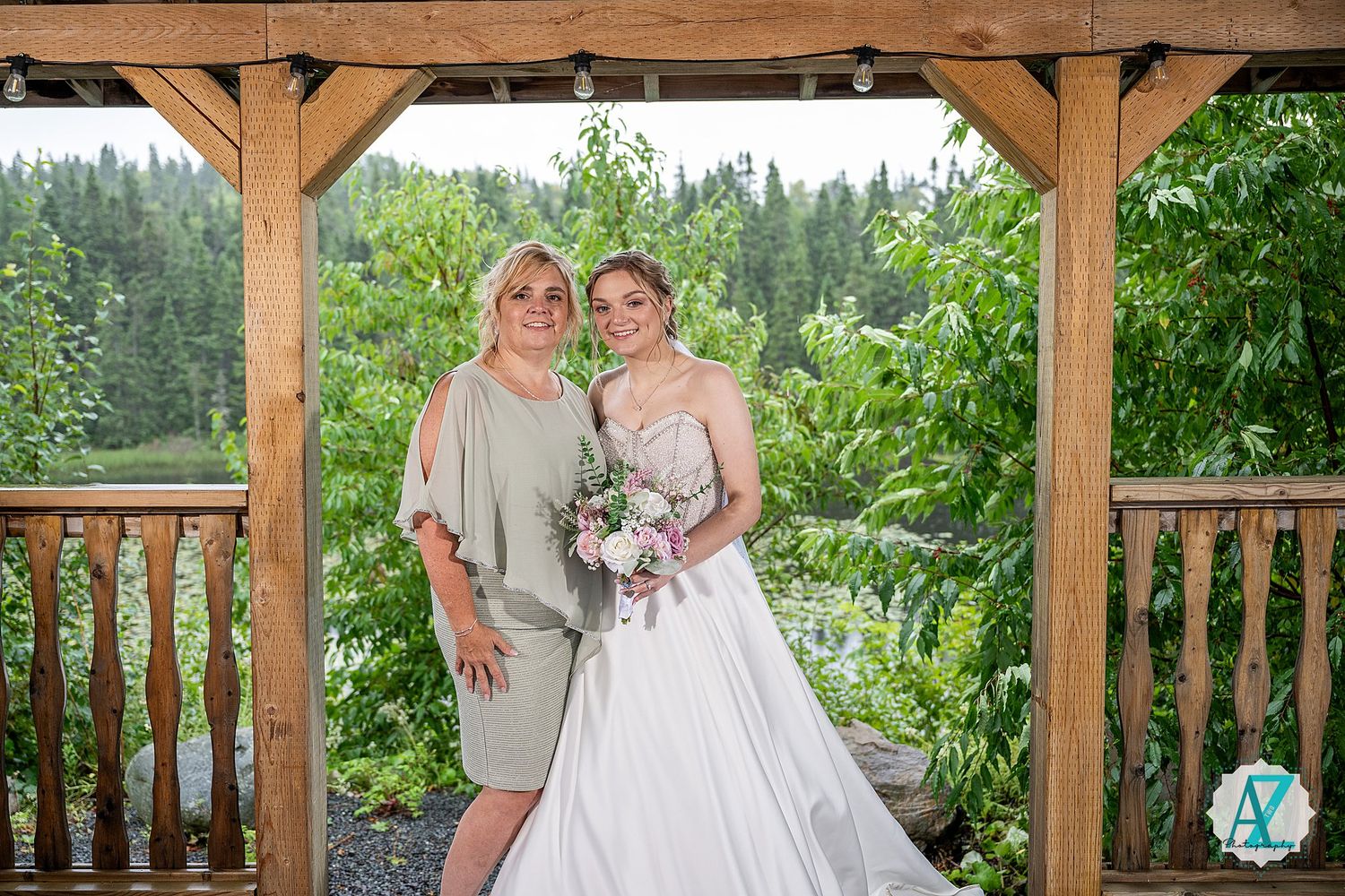 A wedding scene under a wooden gazebo overlooking a forested landscape with a beautiful floral bouquet.