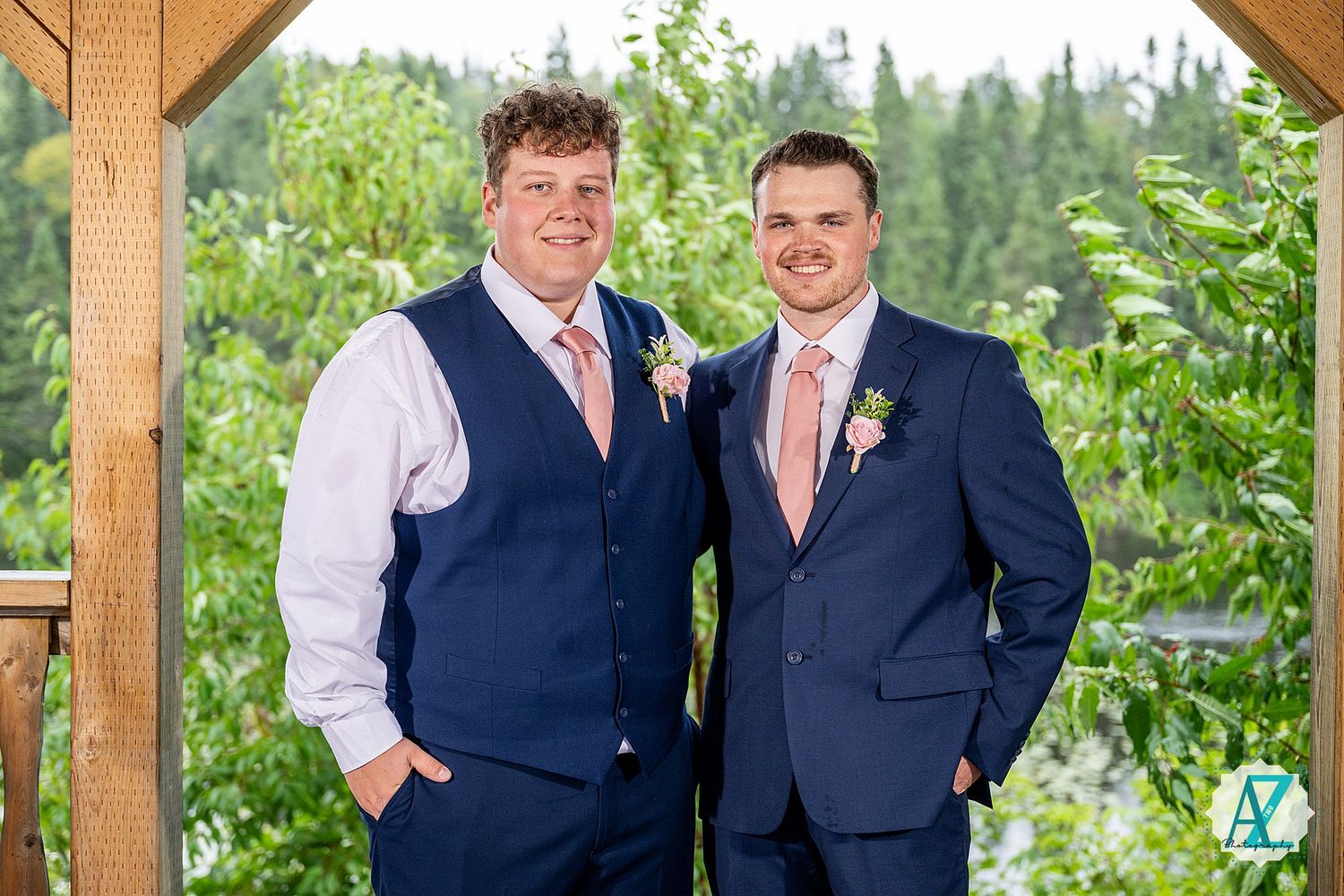 Groomsmen wearing navy vests and suits pose together in an outdoor garden setting during a wedding celebration.