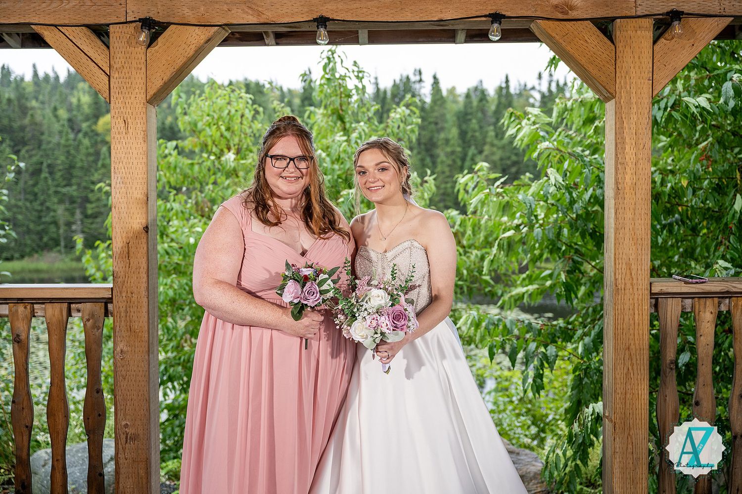 Wedding photography in a rustic wooden gazebo with floral bouquet details and pink dress accents.