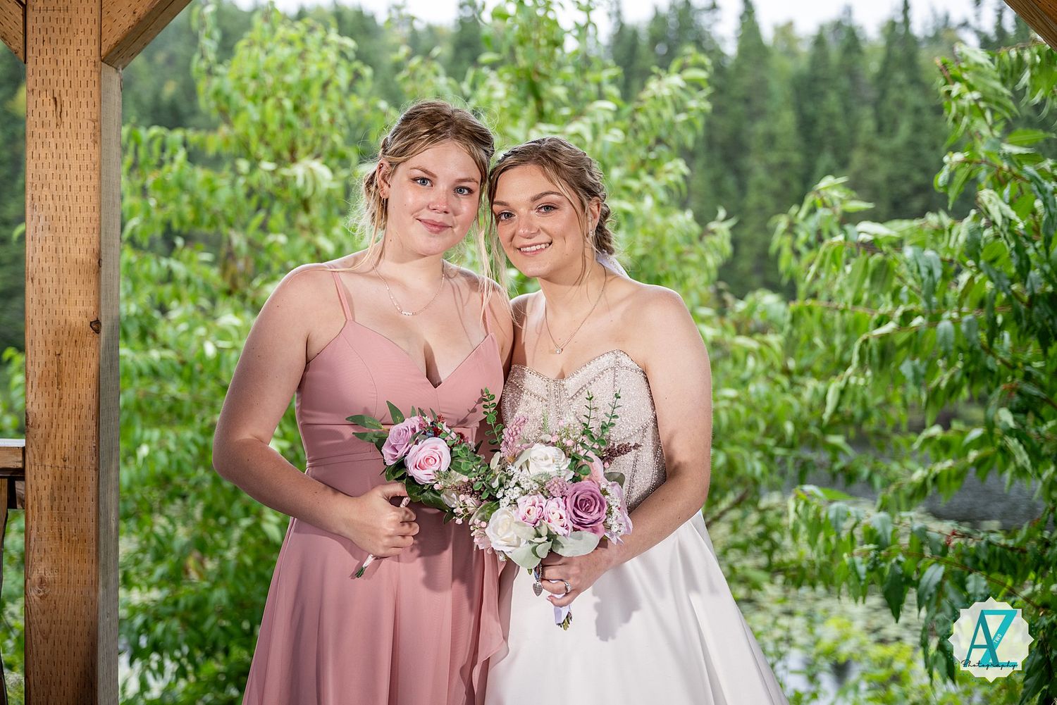 Wedding party members in pink dresses pose together in a garden setting with floral bouquets.