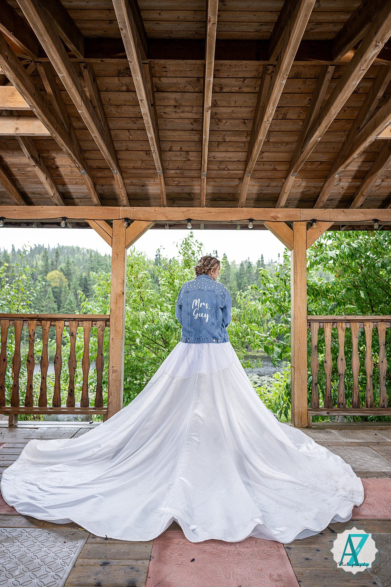 Five elegant white wedding dresses arranged in a row under a rustic wooden pavilion.