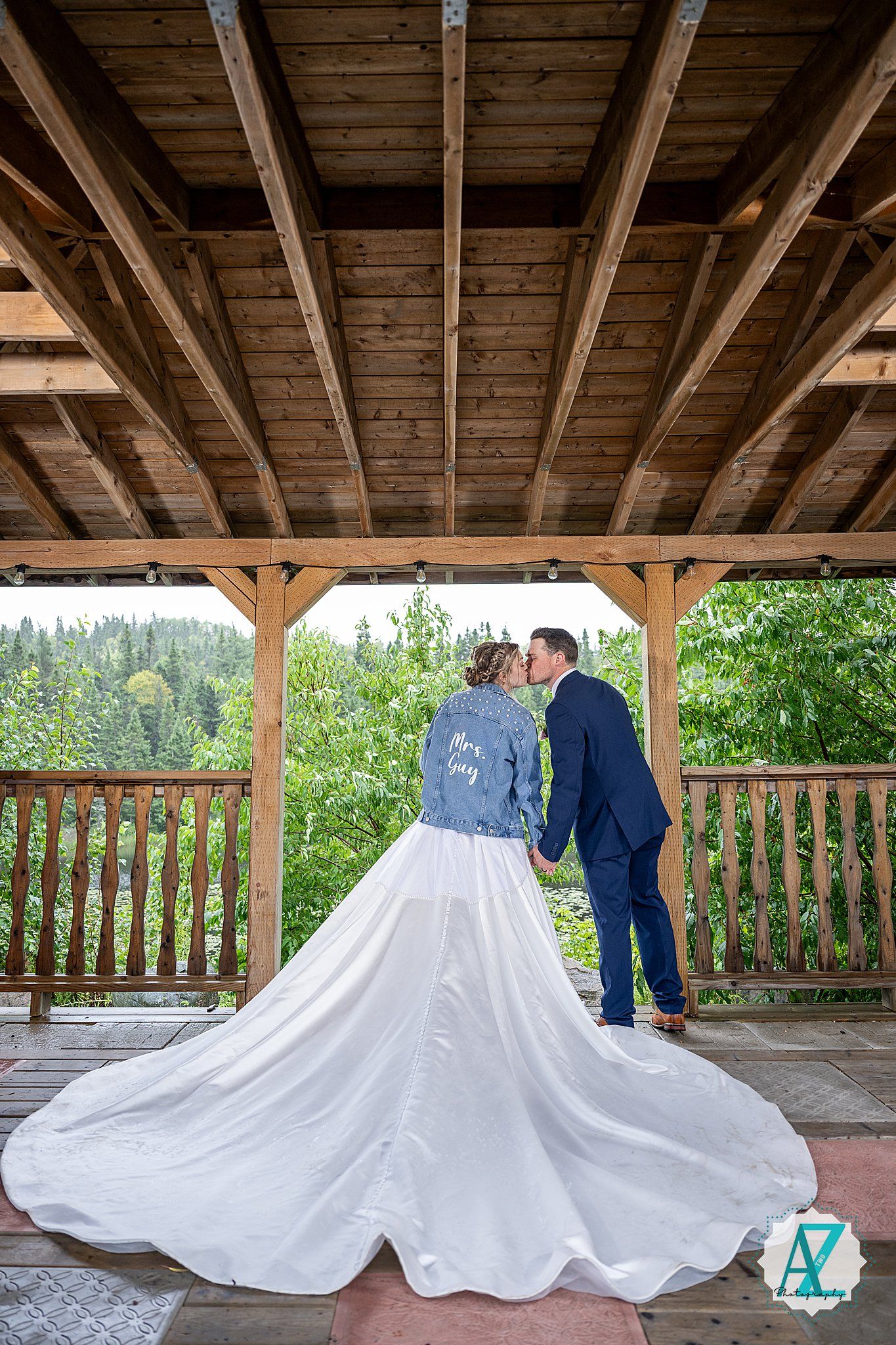 Wedding party poses on a covered wooden deck with the bridal gown's train elegantly arranged.